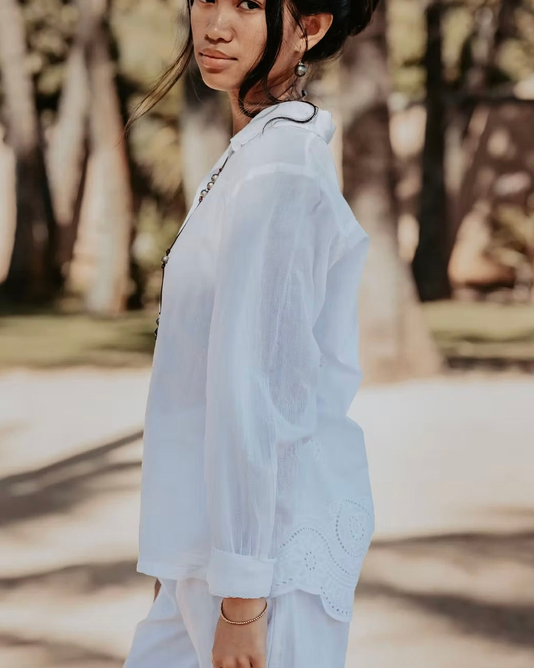 Woman wearing a white outfit with a blurred natural background
