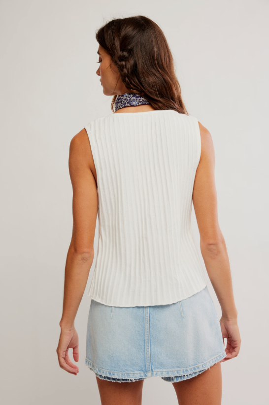 Woman wearing a white sleeveless ribbed top and light blue denim skirt on a plain background