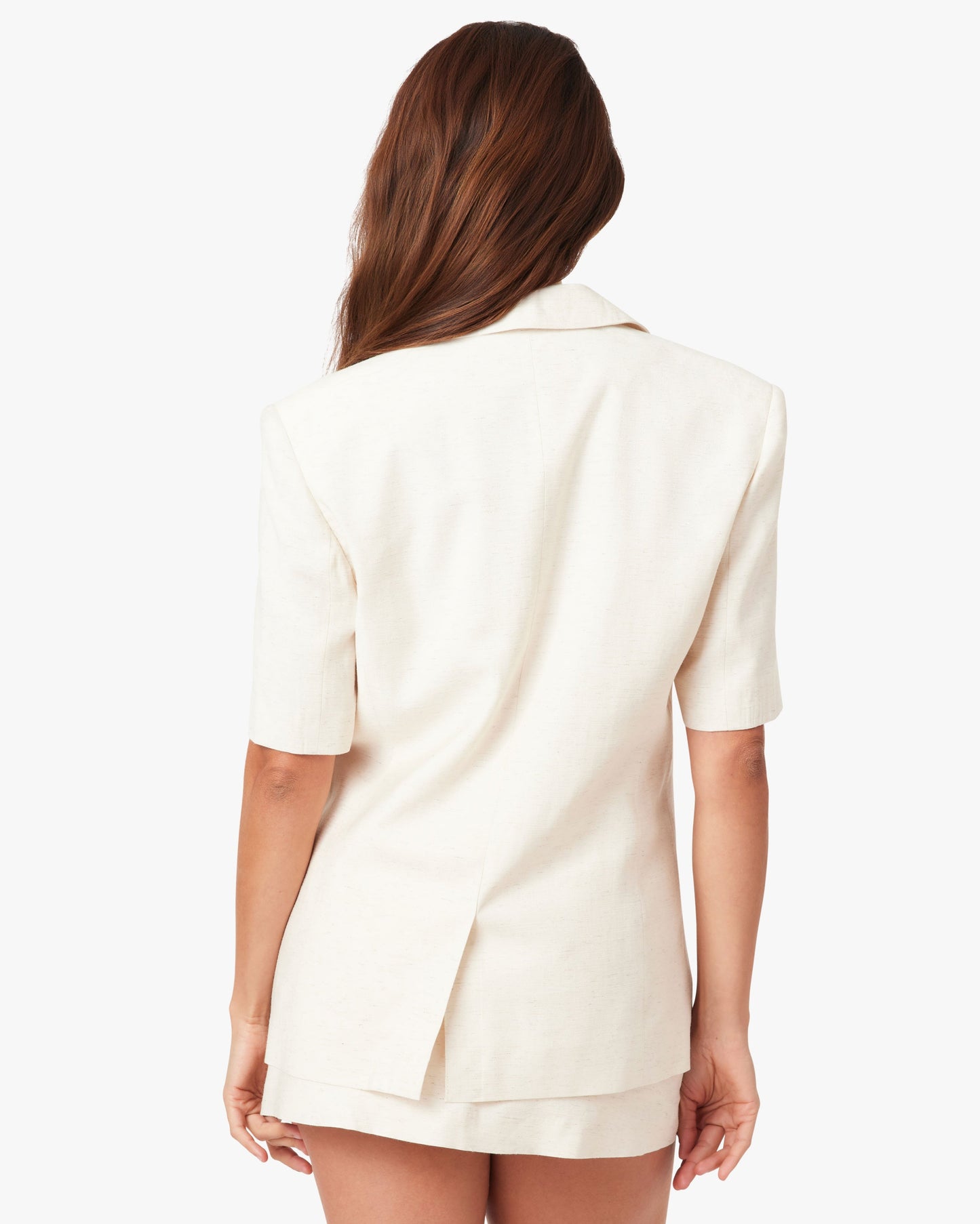 Woman wearing a cream-colored blazer on a white background