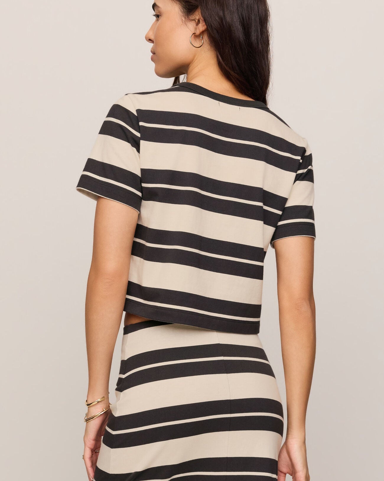 Woman wearing a black and beige striped dress against a plain background