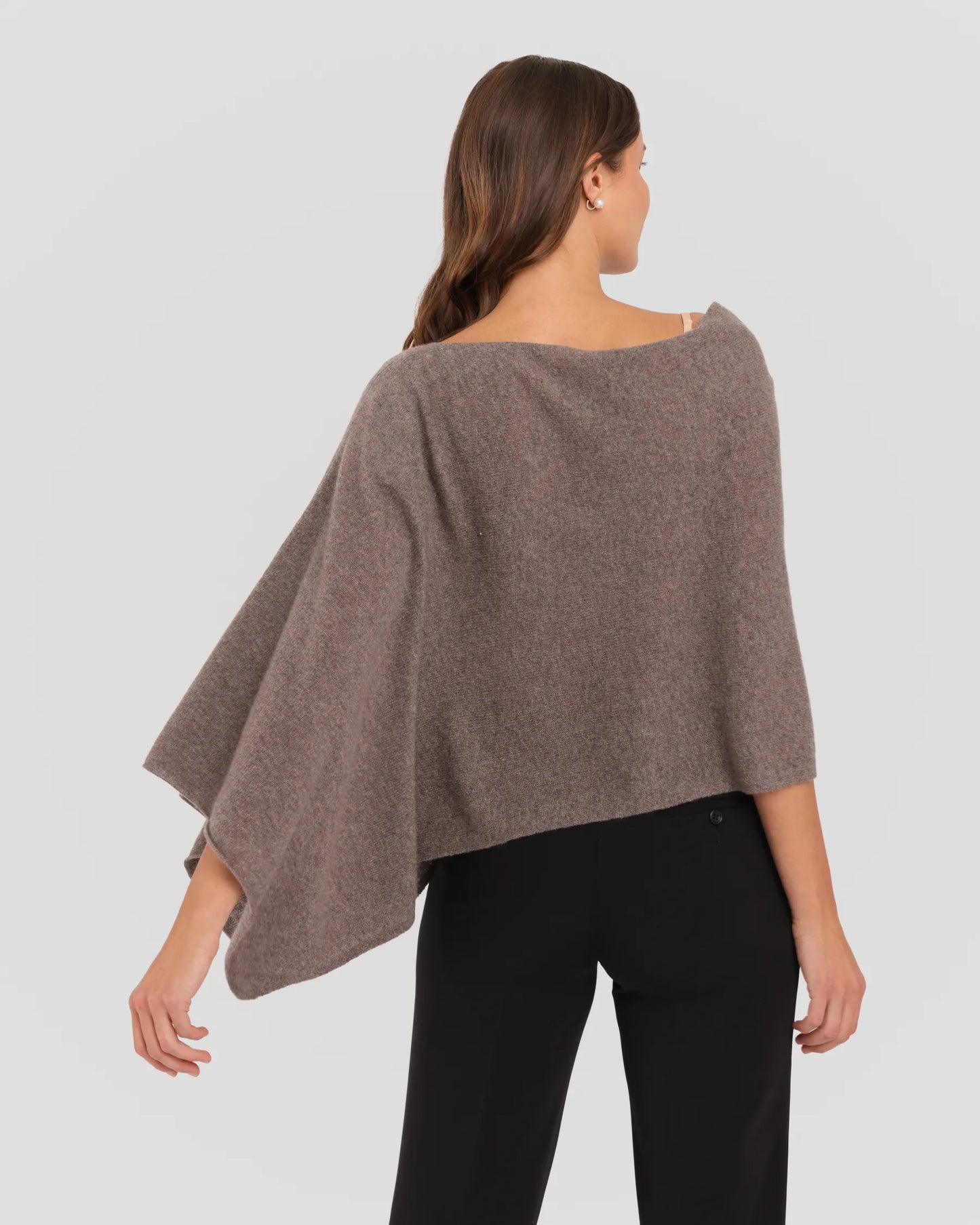 Woman wearing a brown poncho against a white background