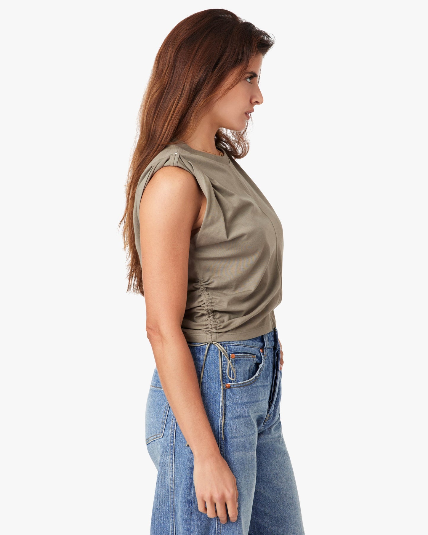 Woman wearing a green sleeveless top and blue jeans on a white background