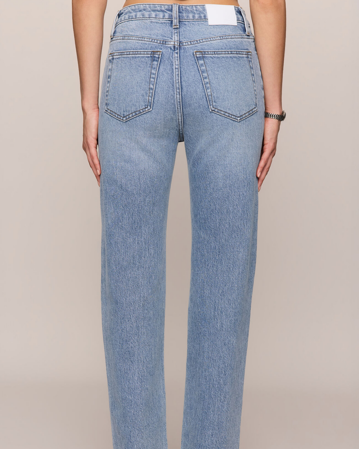 Light blue jeans worn by a person on a beige background