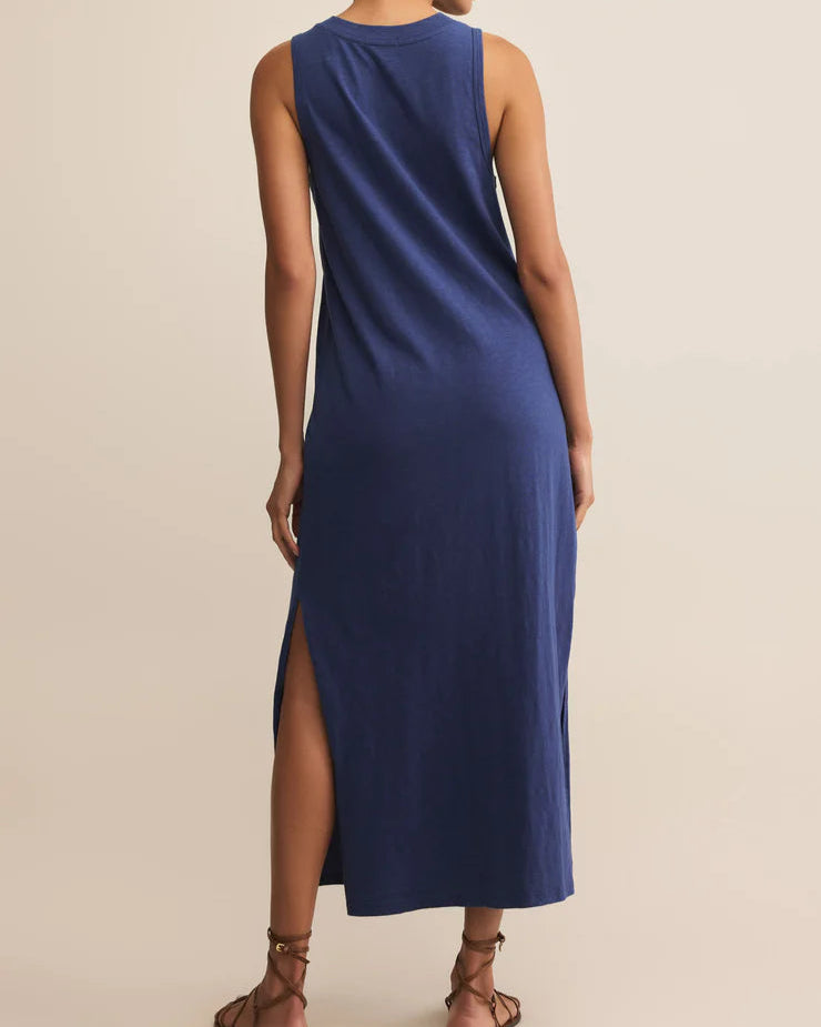 Woman wearing a blue sleeveless dress with a slit on a beige background