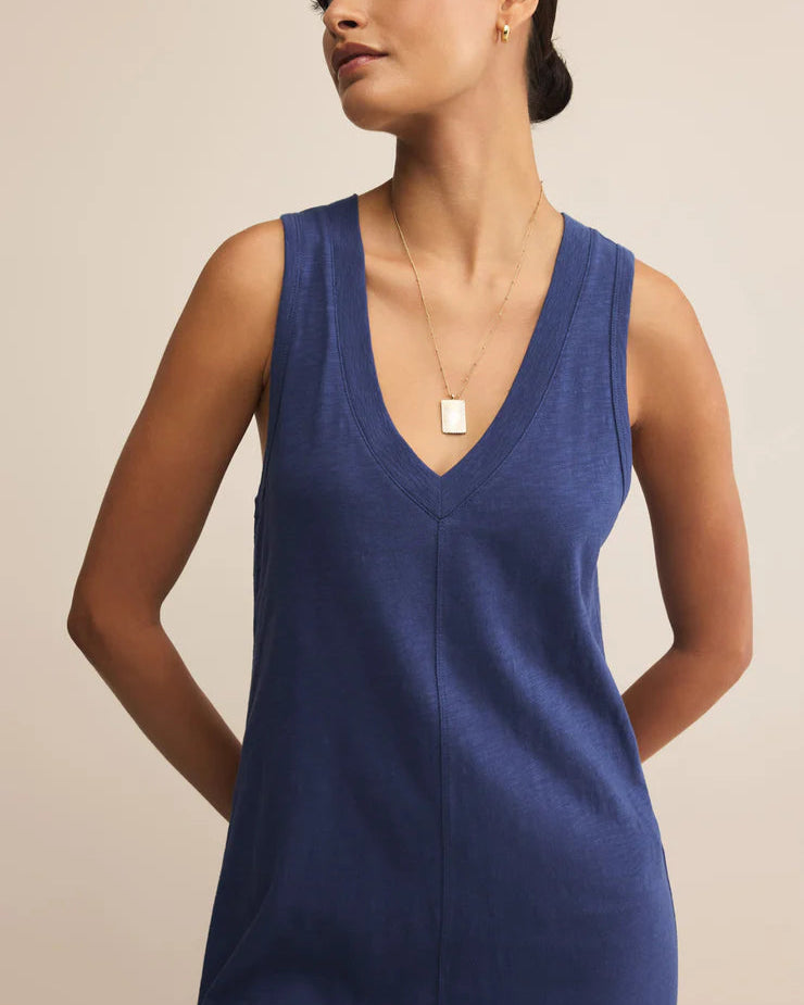 Woman wearing a blue sleeveless dress against a beige background