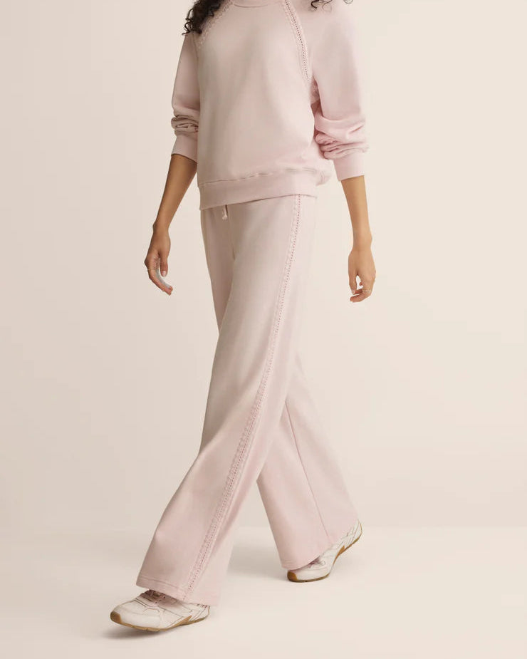 Woman wearing a light pink outfit on a beige background