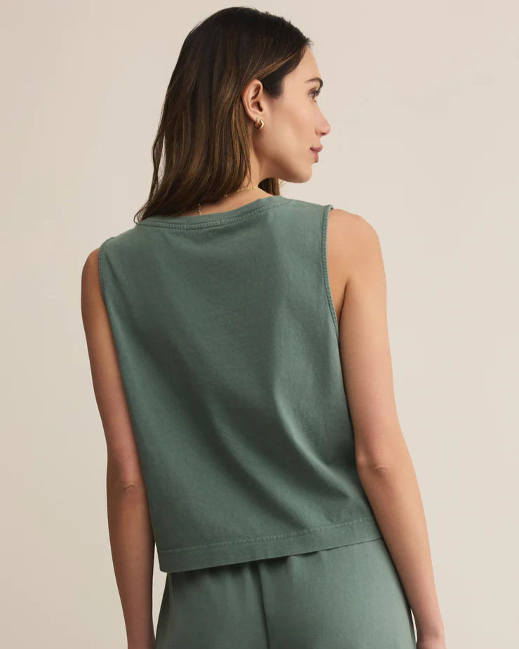 Woman wearing a green sleeveless top and pants on a beige background