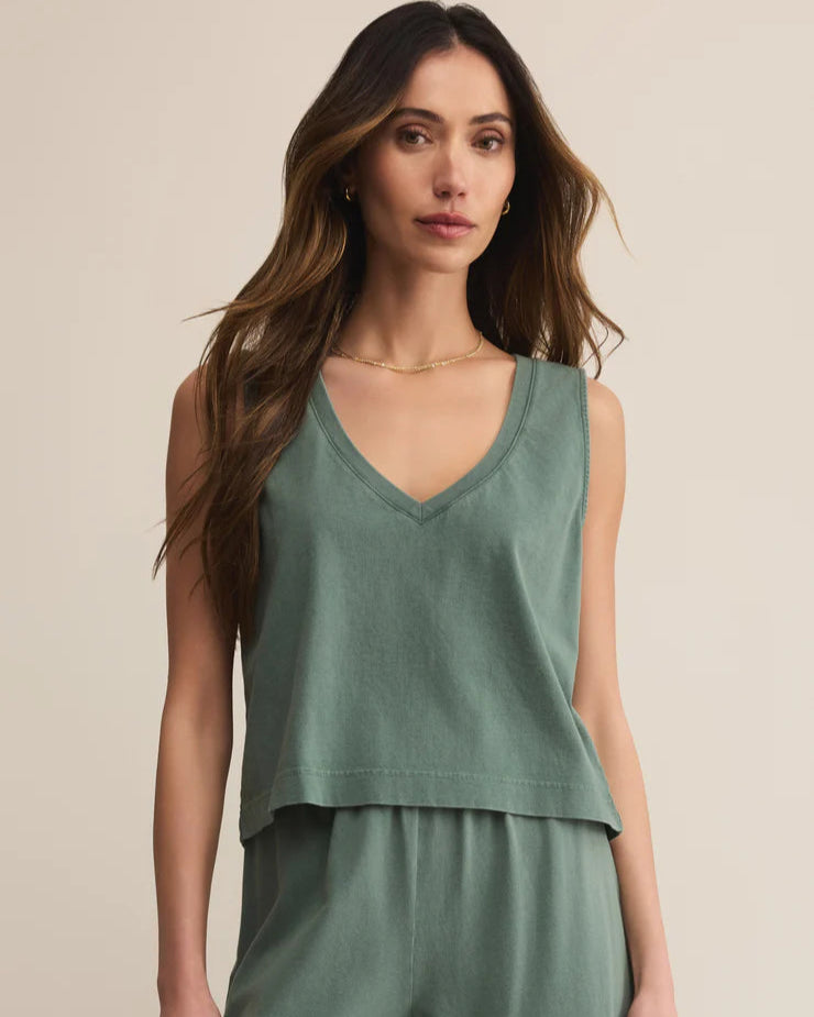 Woman wearing a green sleeveless top and pants against a beige background