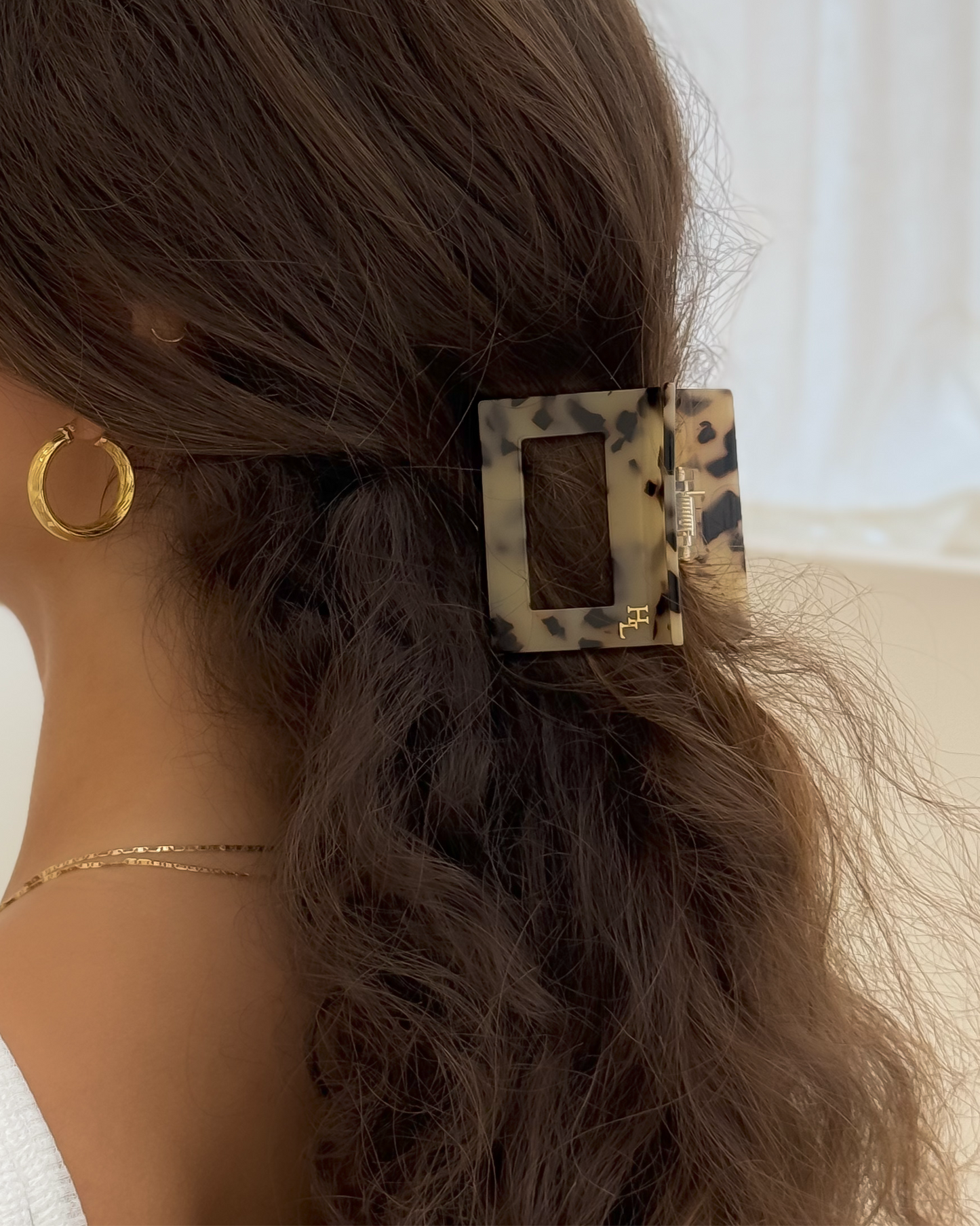 Woman wearing the HoneyLux Dolce Large Acetate Claw clip in the color Classic Tortoise against a neutral background
