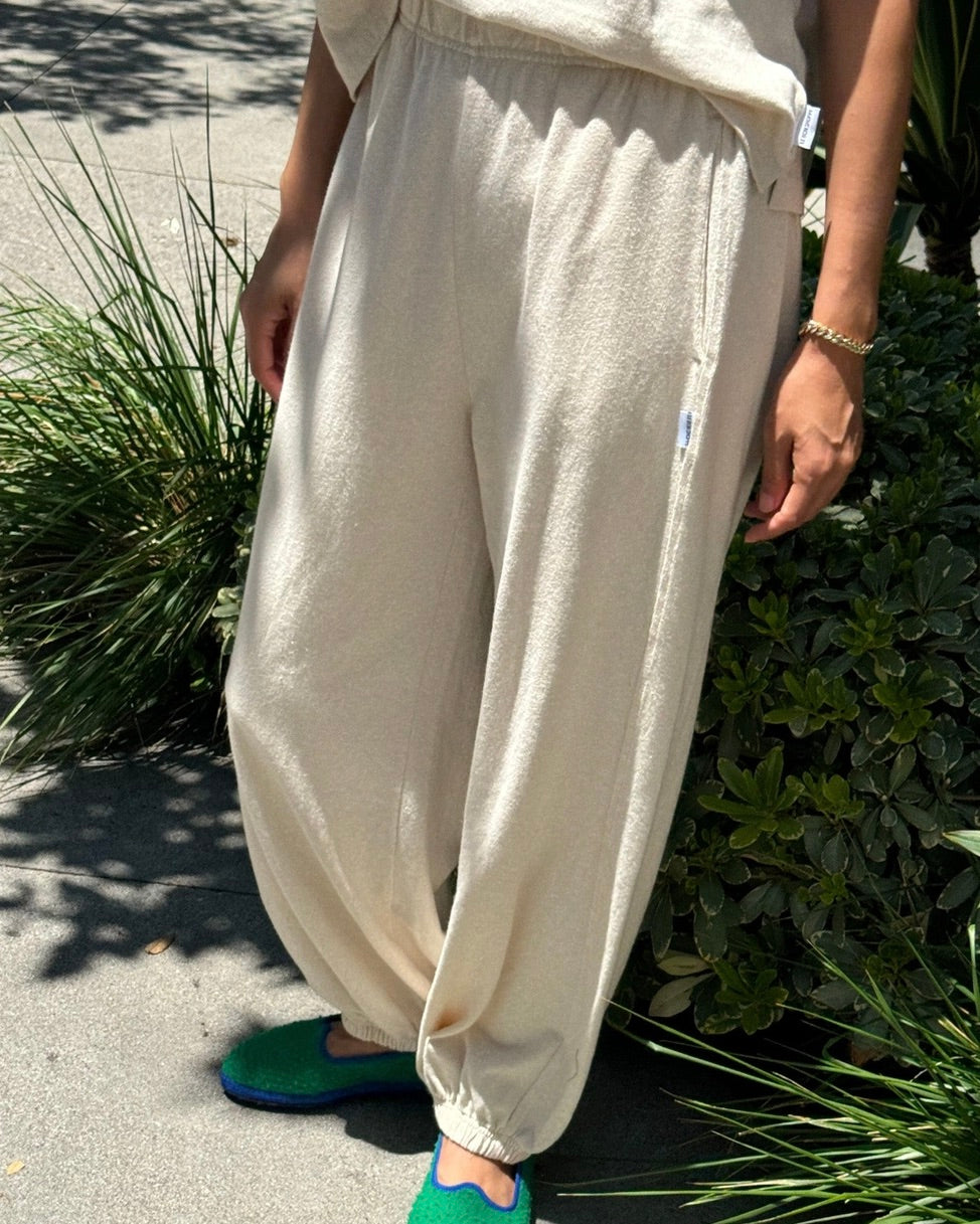 Front view of a model wearing the Le Bon Shoppe balloon pant in naturel standing outside in front of plants.