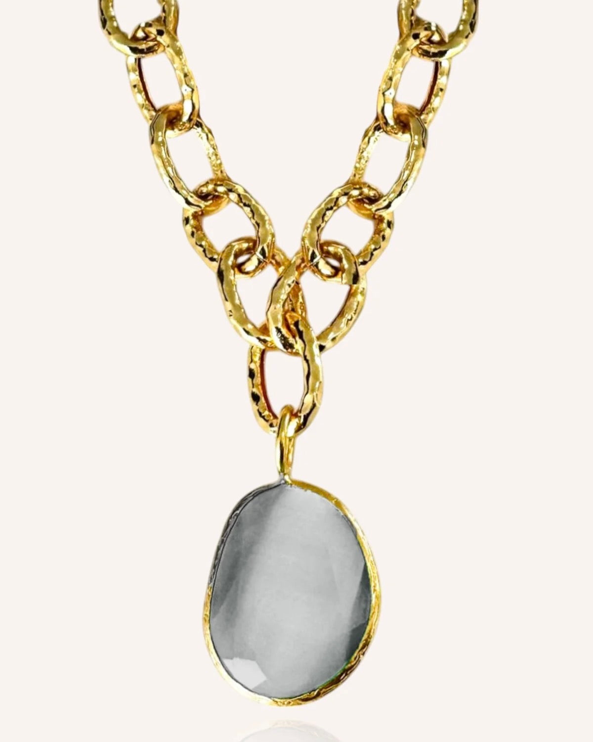 Gold chain necklace with a gray pendant on a white background