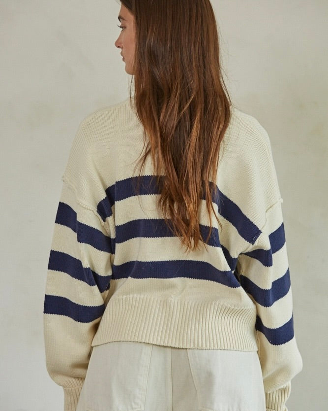 Back view of model wearing the By Together Knit Sweater Striped Button Down Cardigan against a beige wall