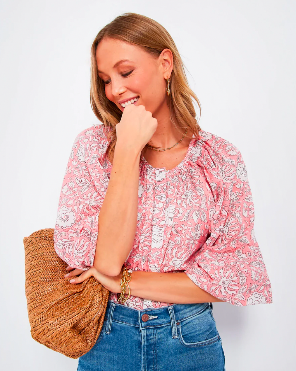 Model wearing Emerson Fry Frances Blouse in Devins flowers pink organic wearing jeans holding a brown clutch on a white background