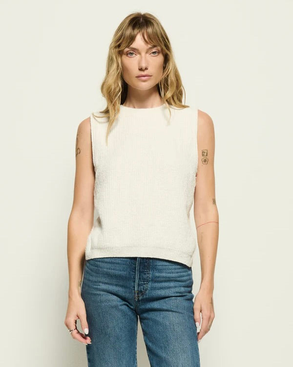 Model wearing the Nation Eliza Sweater Tank with jeans standing in front of a white wall.
