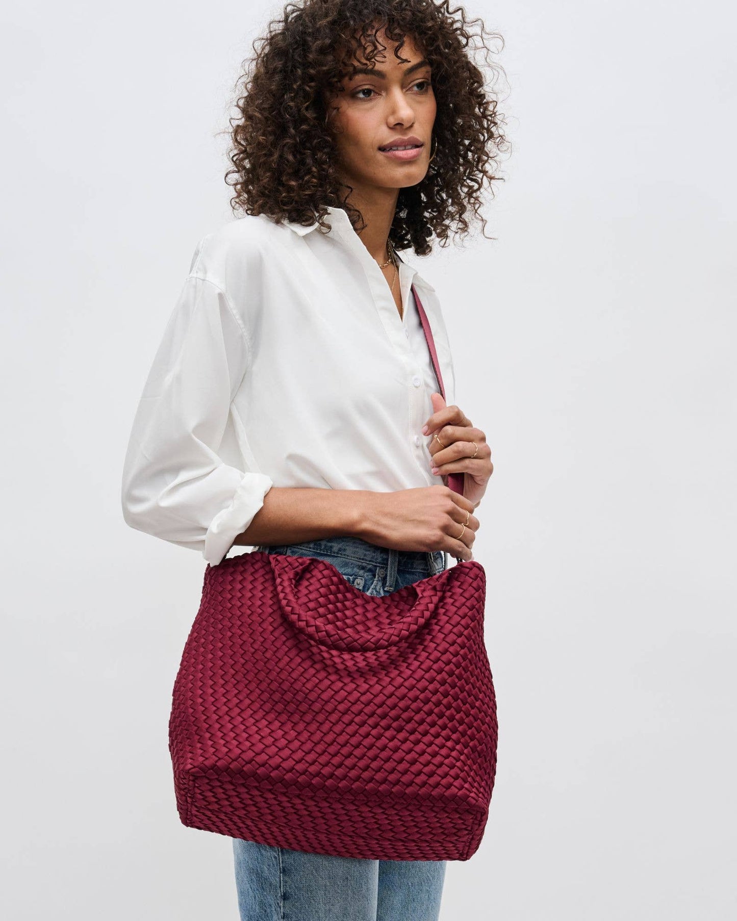 Woman holding a red textured handbag against a plain background