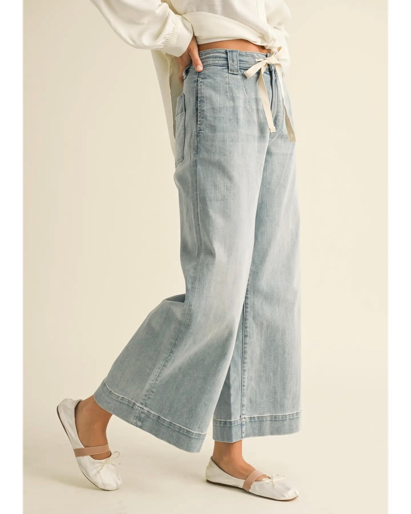 Model is wearing MIOU MUSE Washed Denim Tie Front Pants on a light beige background.