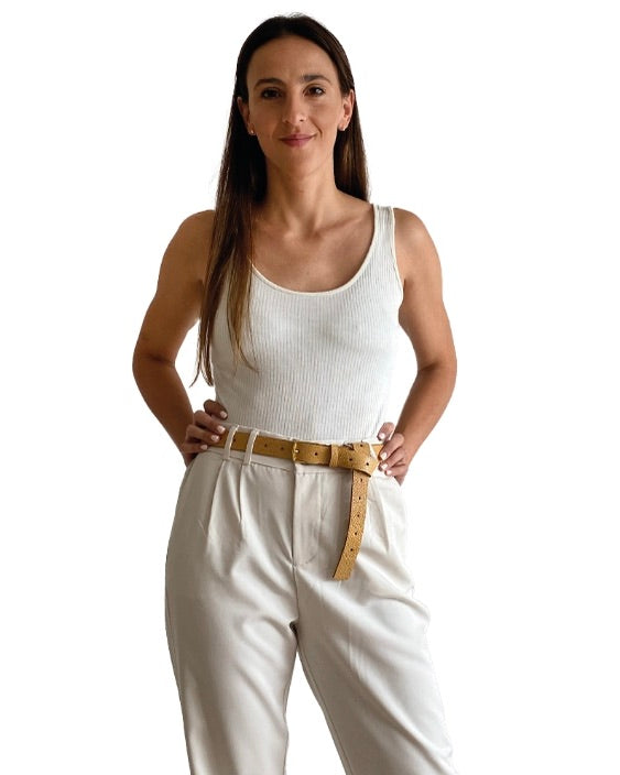 Model wearing the Ada leather detail jean belt with a white tank and neutral pants standing with hands on her hips in front of a white background