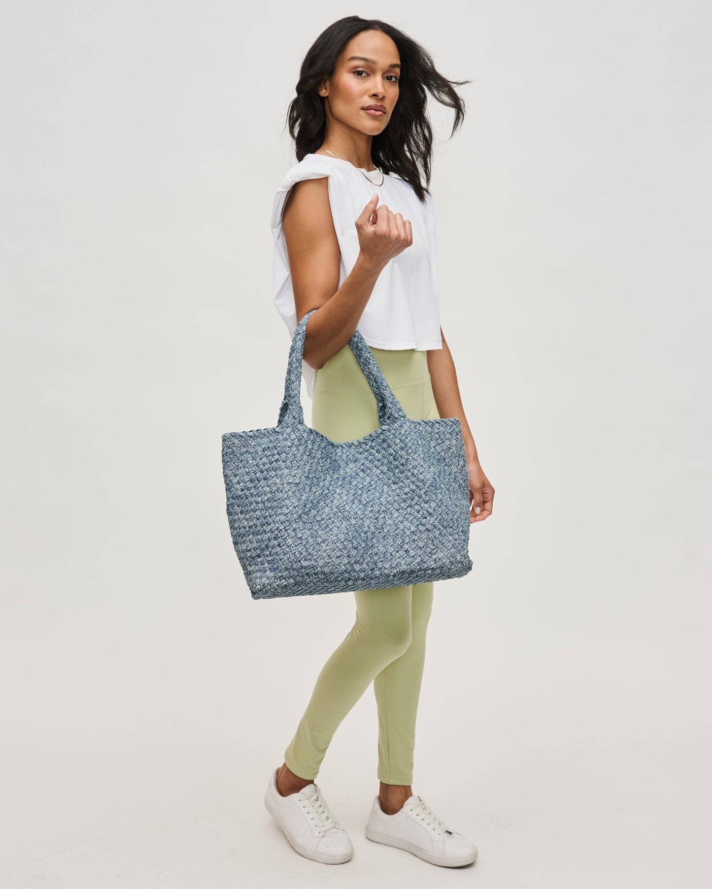 Woman holding a textured blue tote bag against a plain background