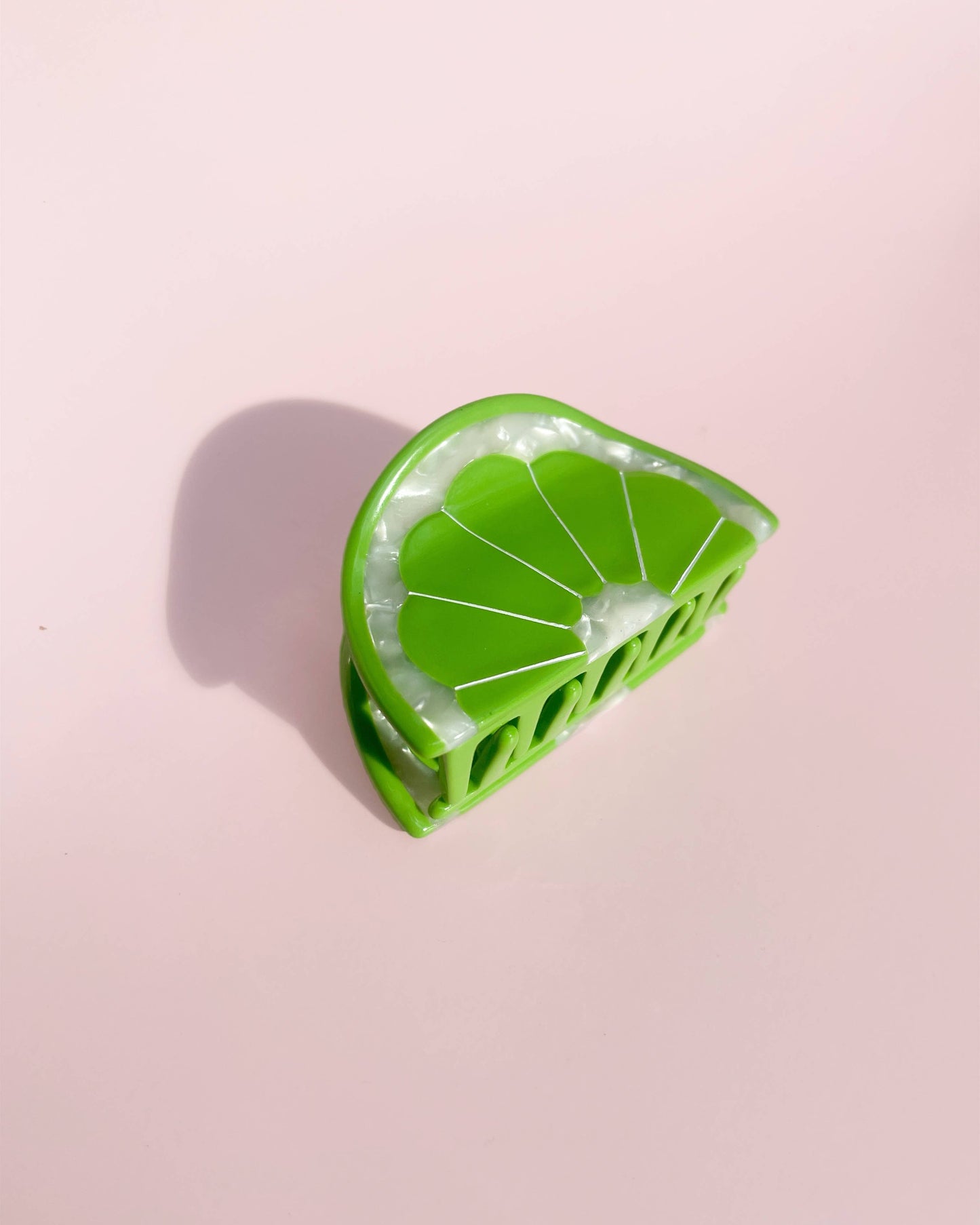 Green lime-shaped hair clip on a pink background