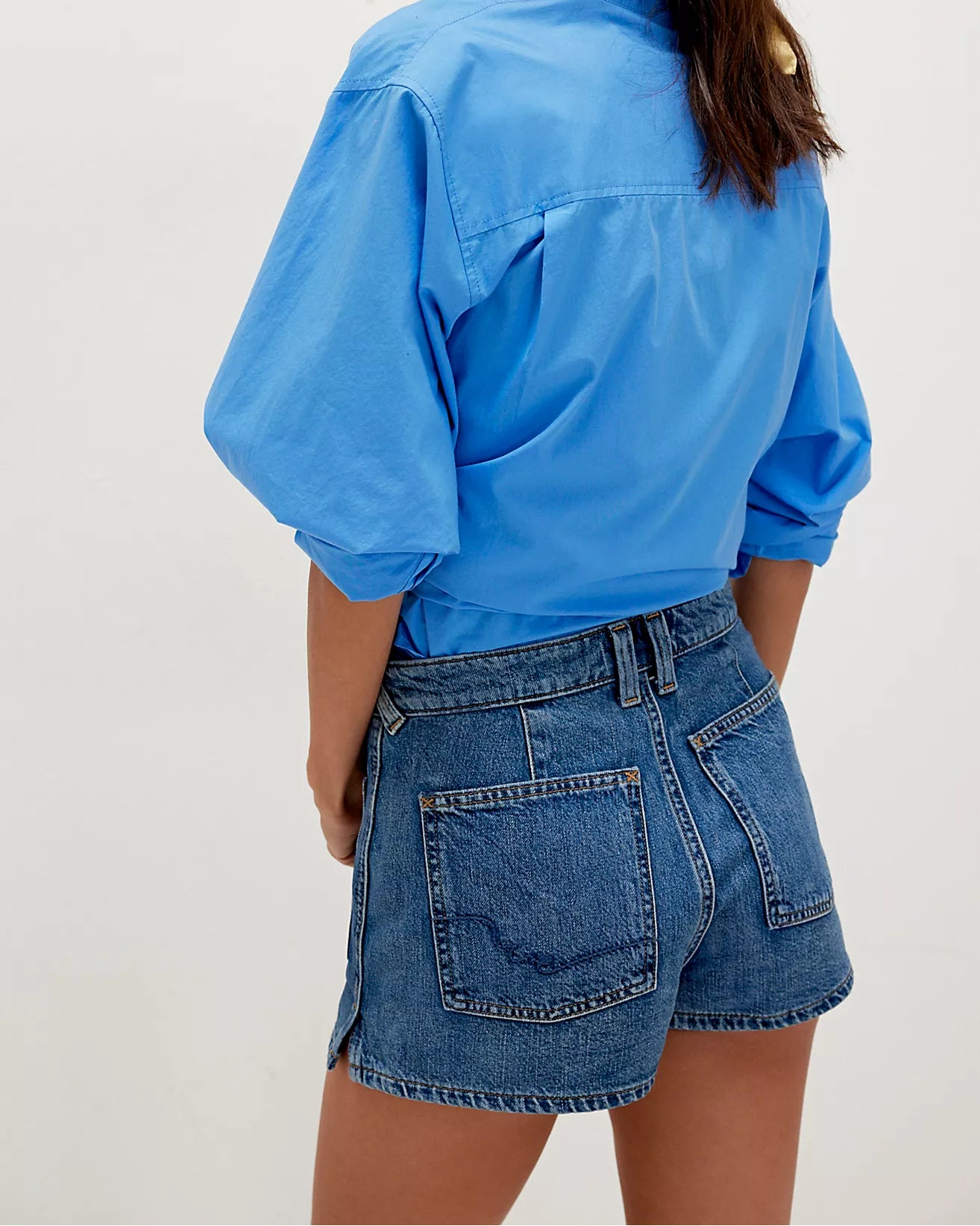 Woman wearing a blue shirt and denim shorts on a white background