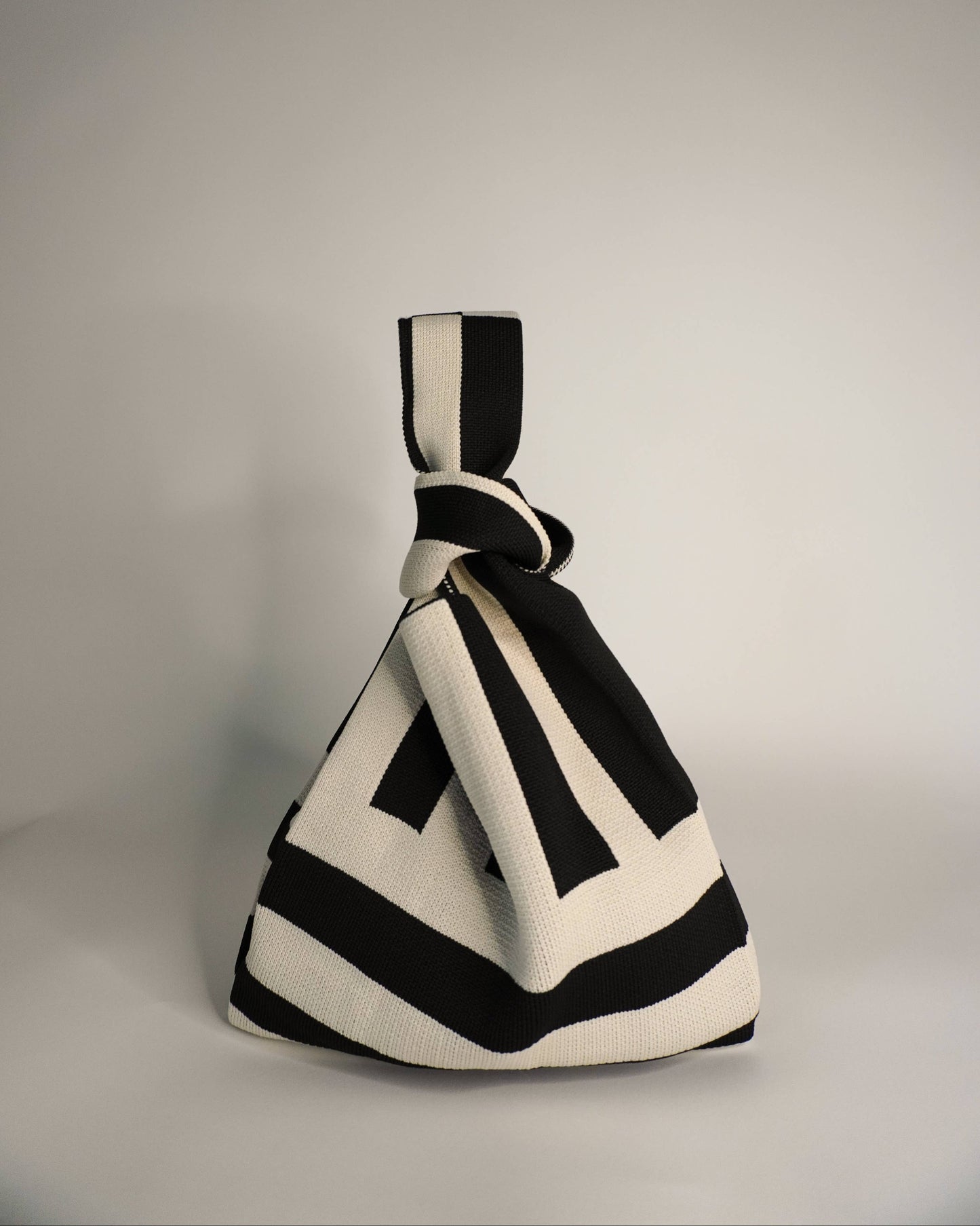Black and white geometric-patterned bag on a gray background