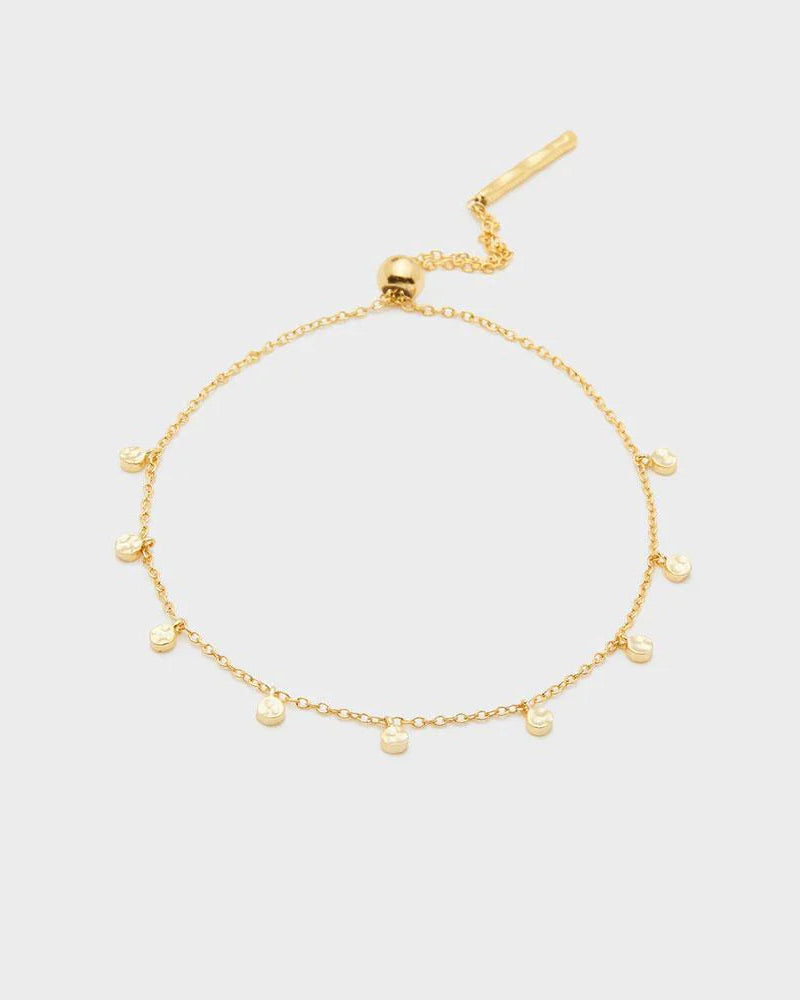 Delicate gold bracelet with small gold charms on white background