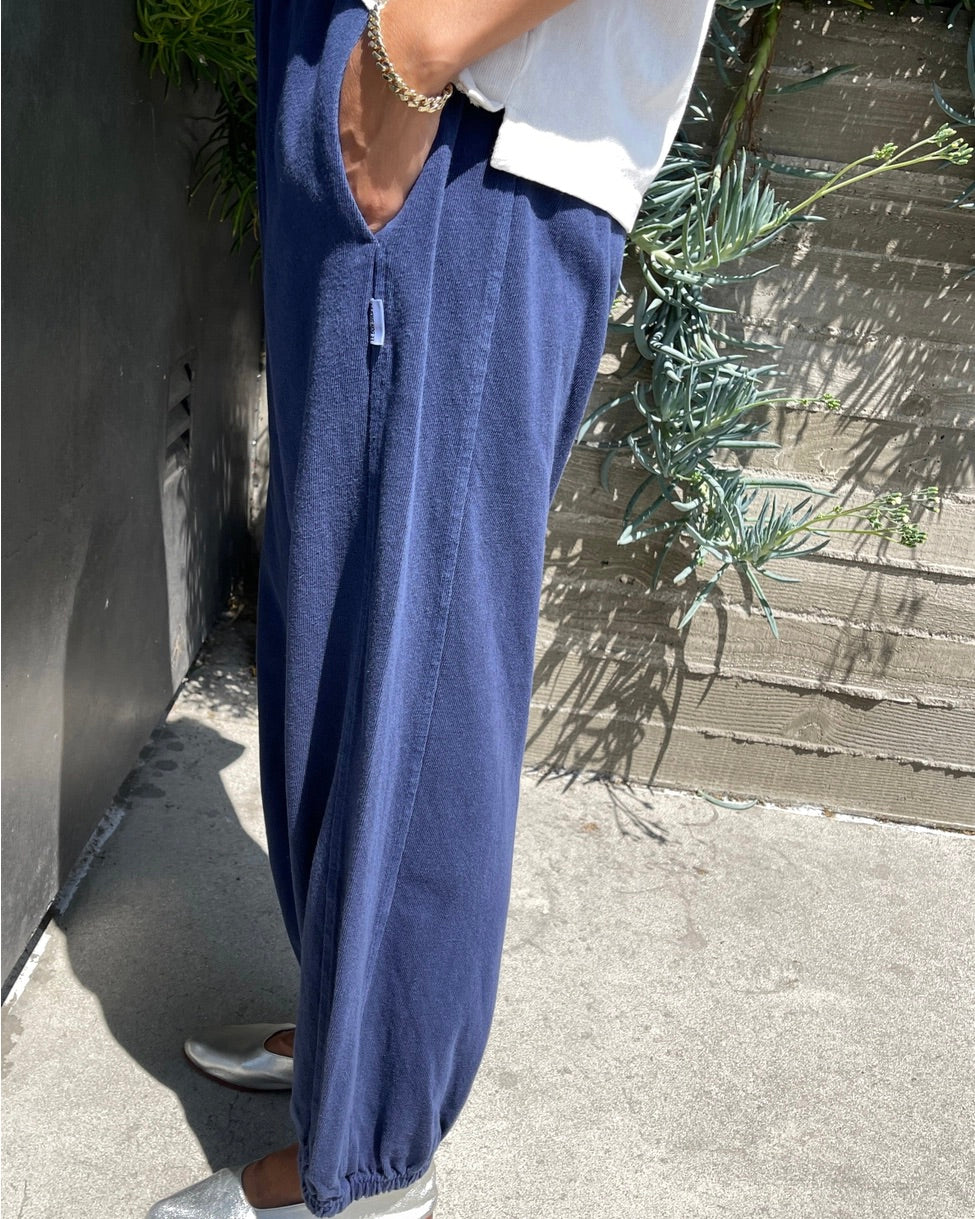 Side view of a model wearing the Le Bon Shoppe balloon pant in midnight standing outside with their hand in their pocket