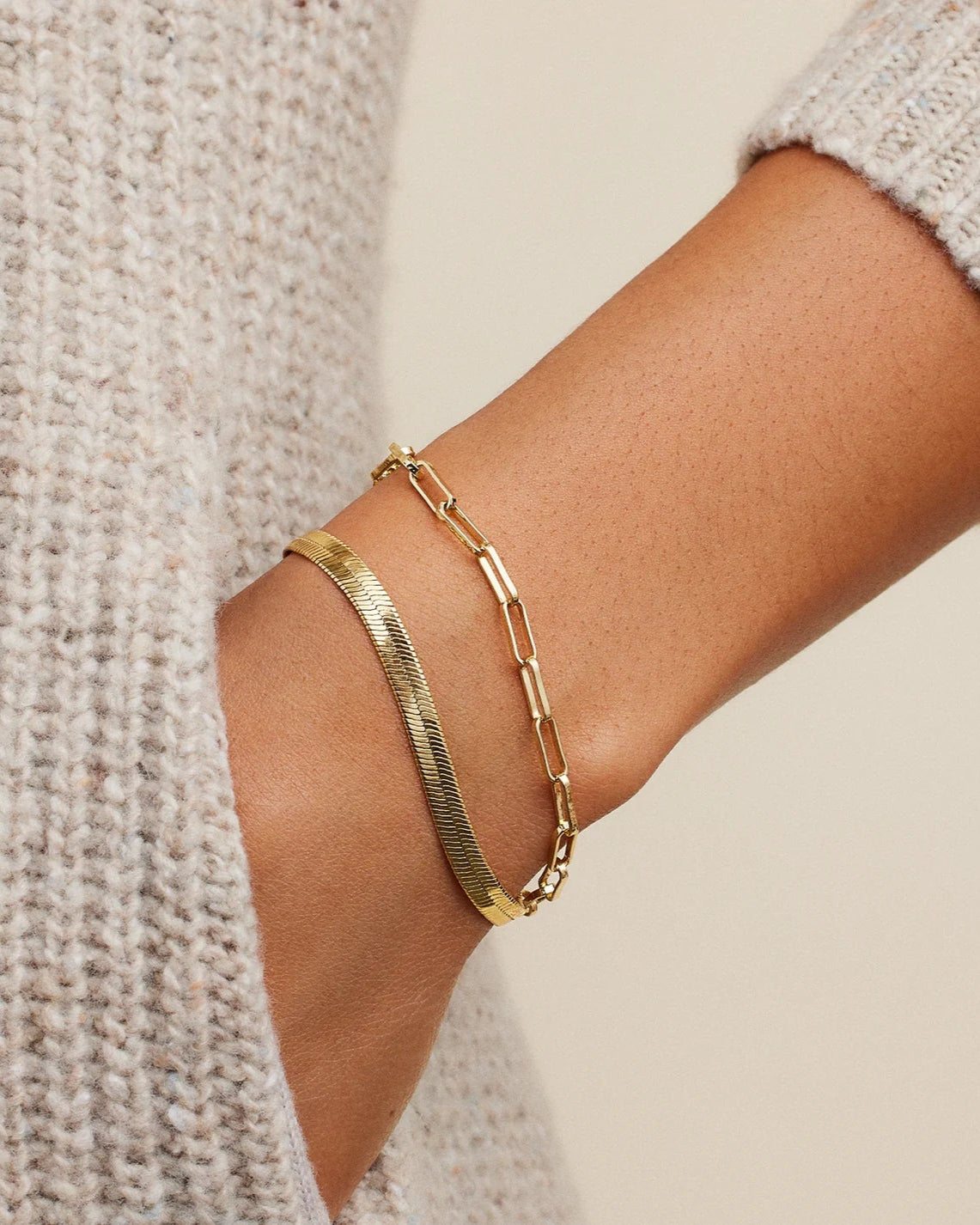 Model is wearing Gorjana Venice Bracelet in gold and a simple gold chain bracelet
