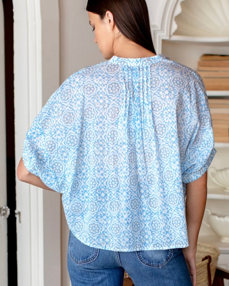 Model wearing Emerson Fry Mandarin Collar Top in Blue Geo Flower color wearing jeans showing the back of the shirt