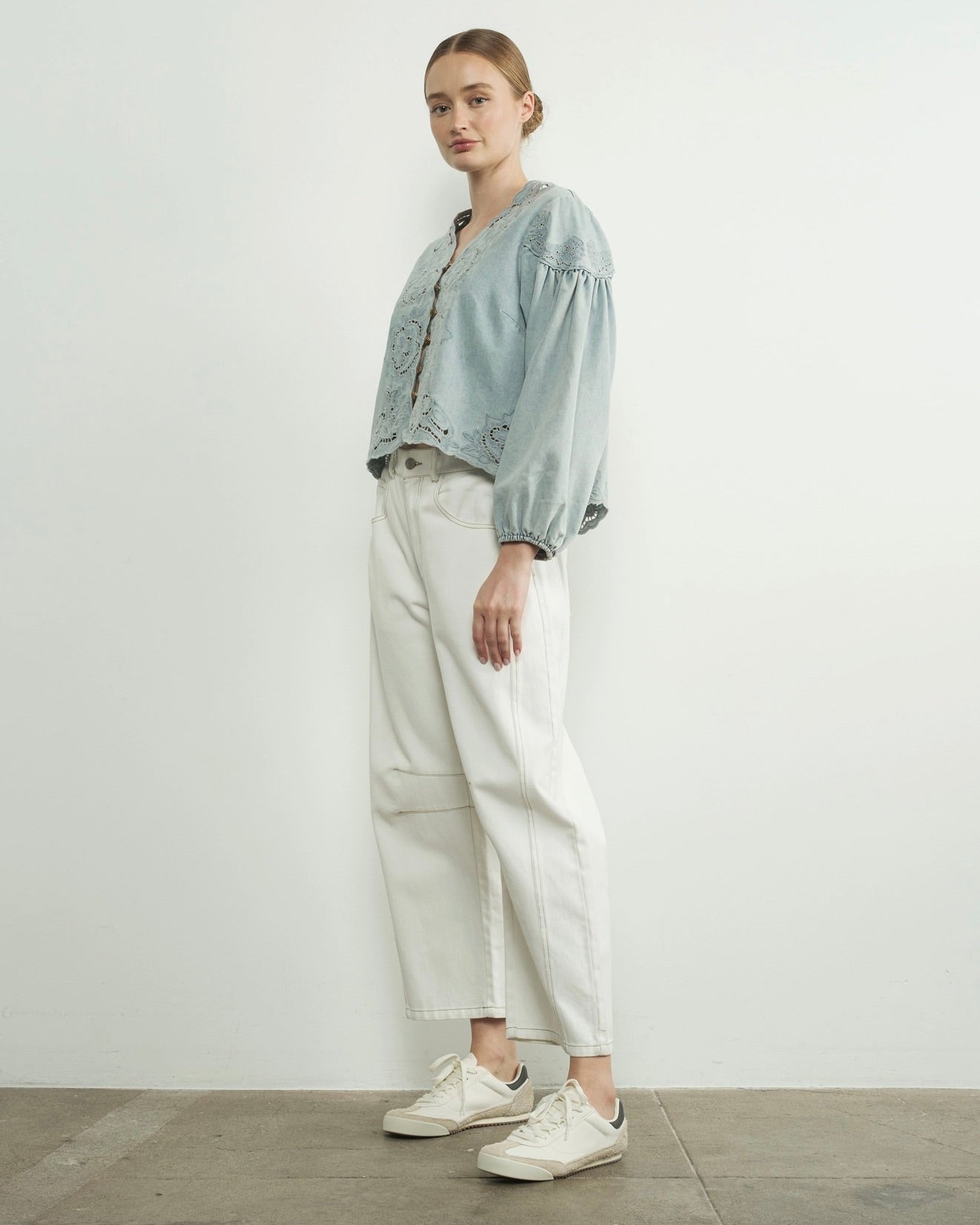 Aaron and amber denim floral embroidery blouse, woman wearing flower embroidered blouse, light blue in front of white wall, white jeans and white shoes, loose summer and spring top