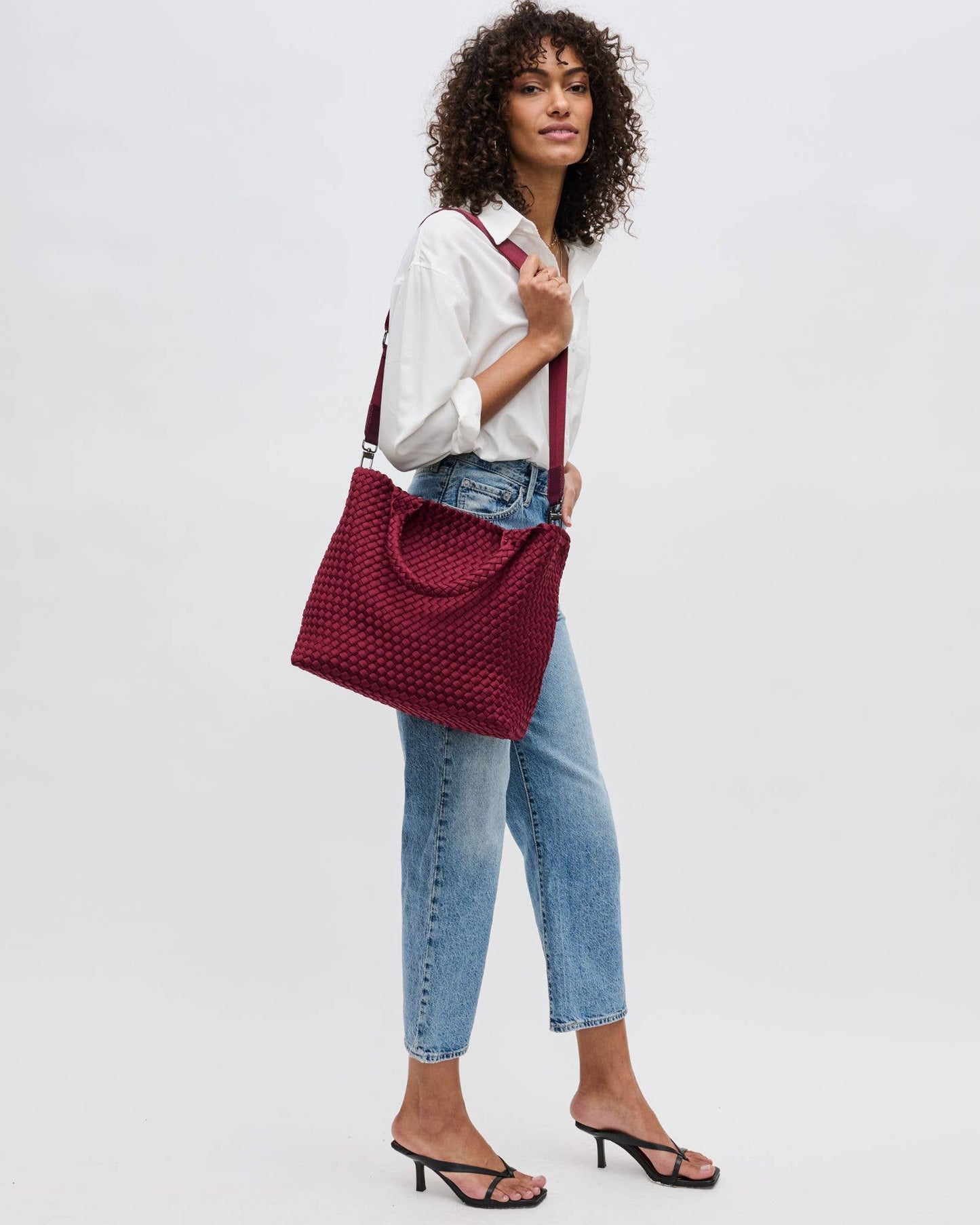 Woman holding a red woven handbag against a white background