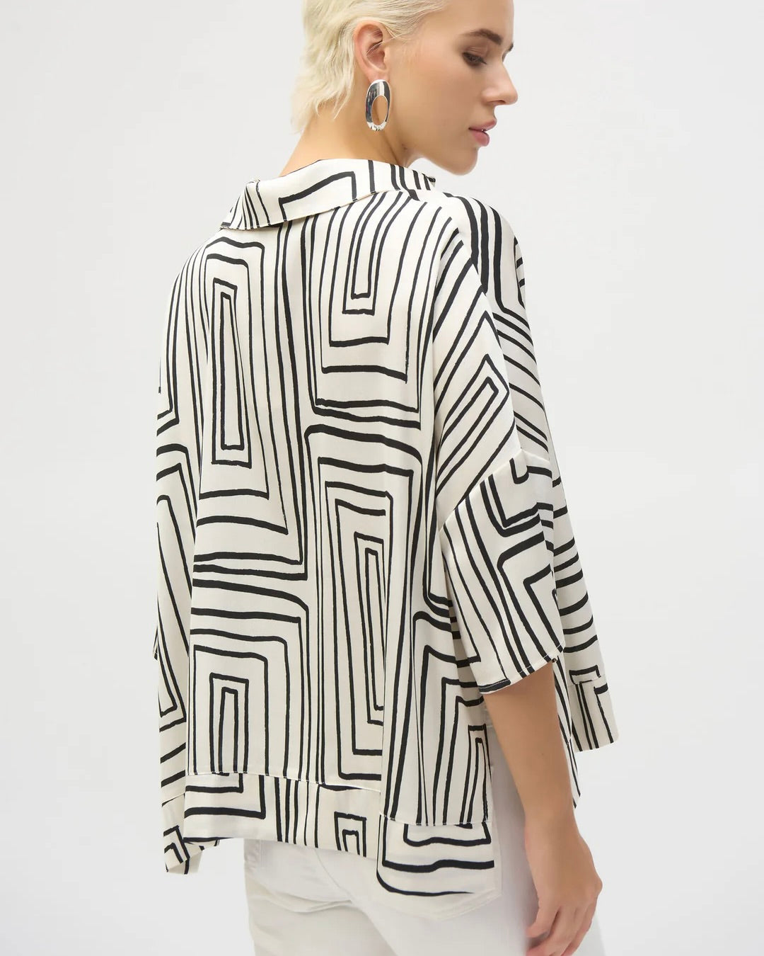 joseph ribkoff geometric boxy top on model in white jeans showing back of top in front of a white wall