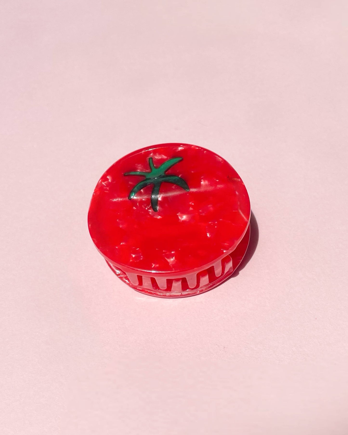 Front view of tomato clip resting on a pink background