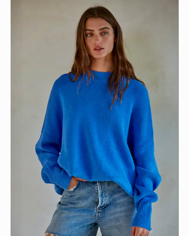 Model wearing By Together Sea Blue Chunky East Street Pullover sweater wearing jeans on a gray background