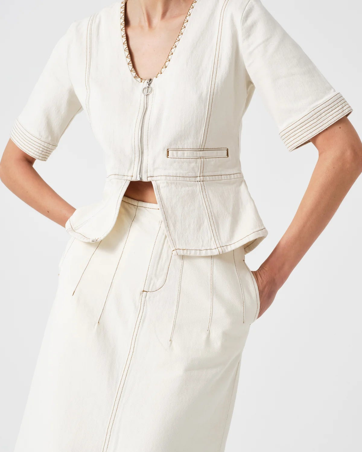 Person wearing a white outfit with a cropped jacket and wide-leg pants on a light gray background