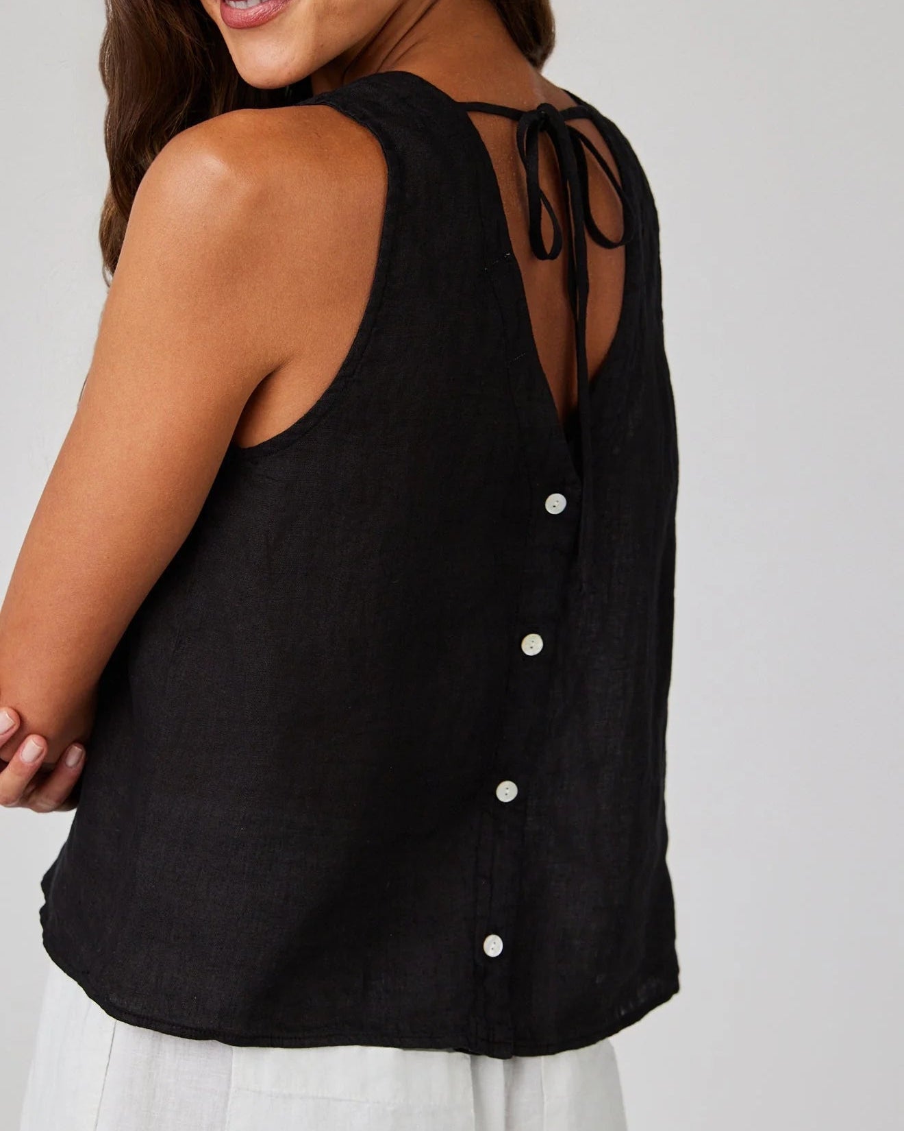 Black sleeveless top with button details on a plain background