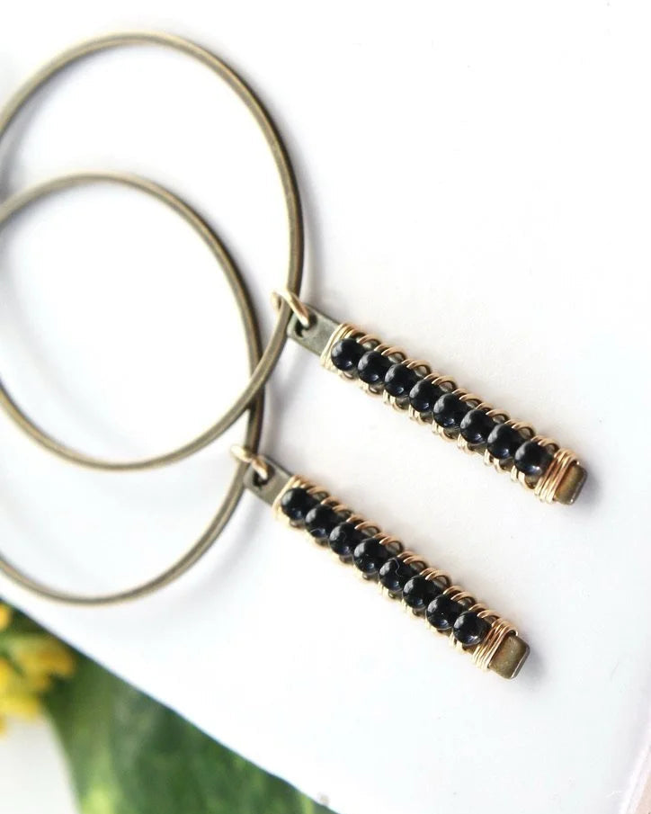 Close up view of the Wild Balance Telluride Earring in the color Onyx resting on a white surface