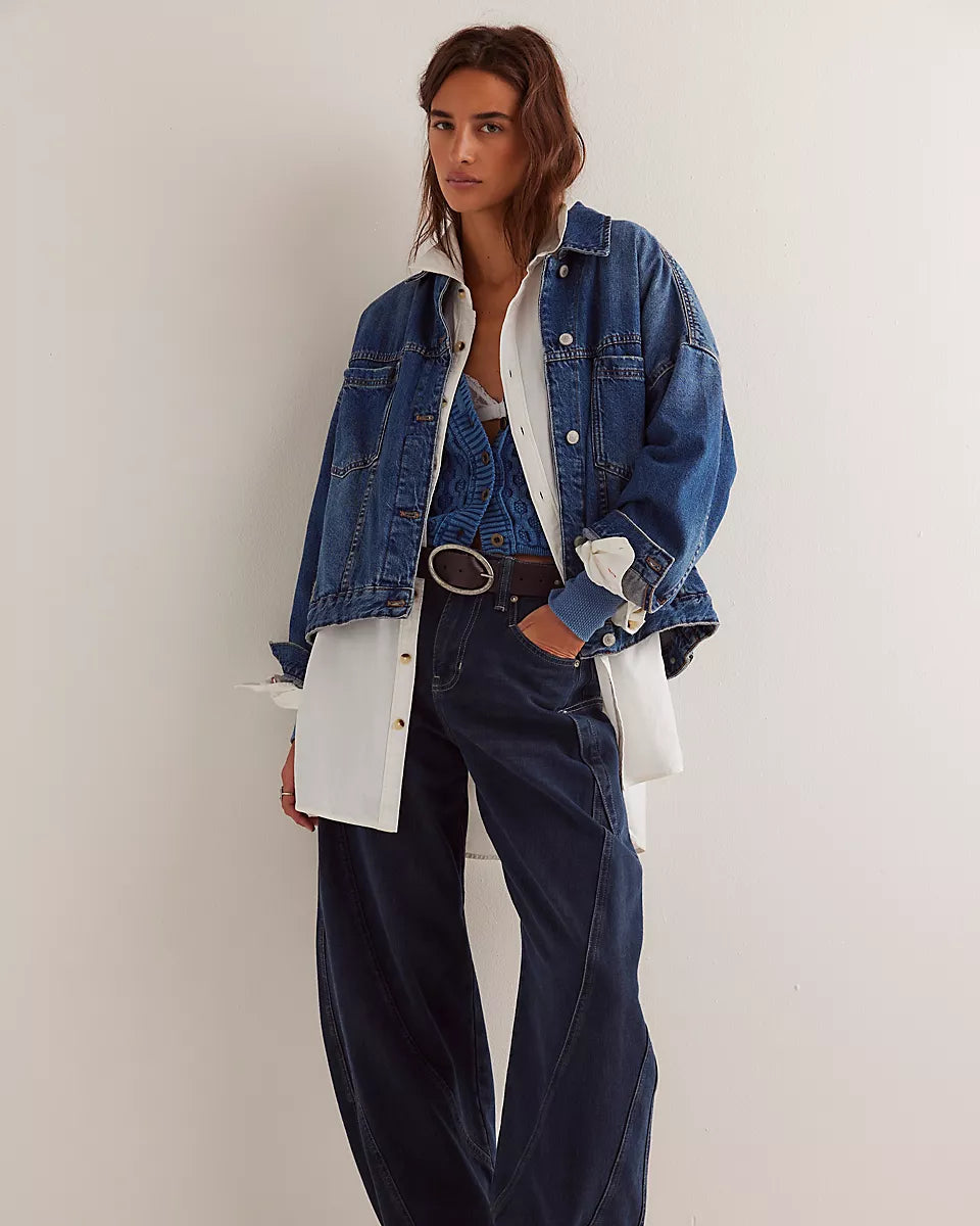 Person wearing a denim jacket, white shirt, and dark jeans against a white background