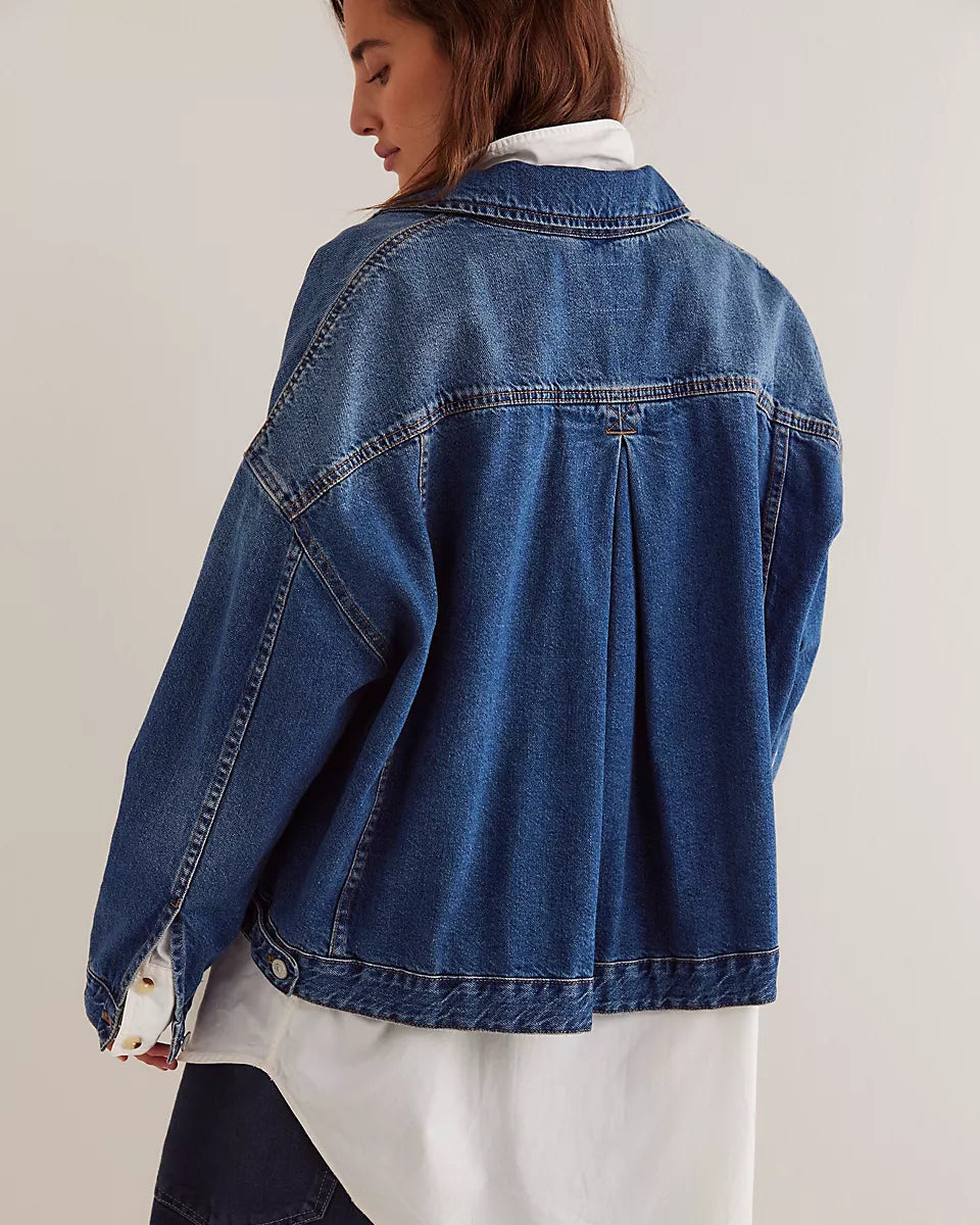 Person wearing a blue denim jacket over a white shirt on a plain background
