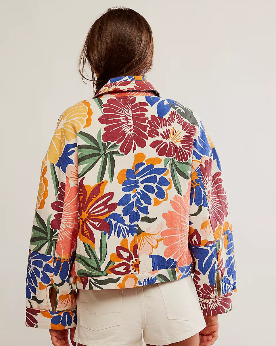 Person wearing a colorful floral jacket on a plain background
