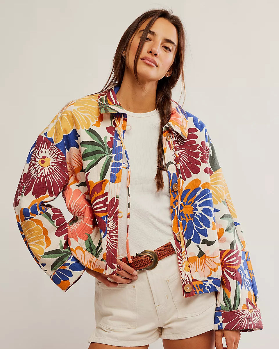 Woman wearing a colorful floral jacket on a plain background