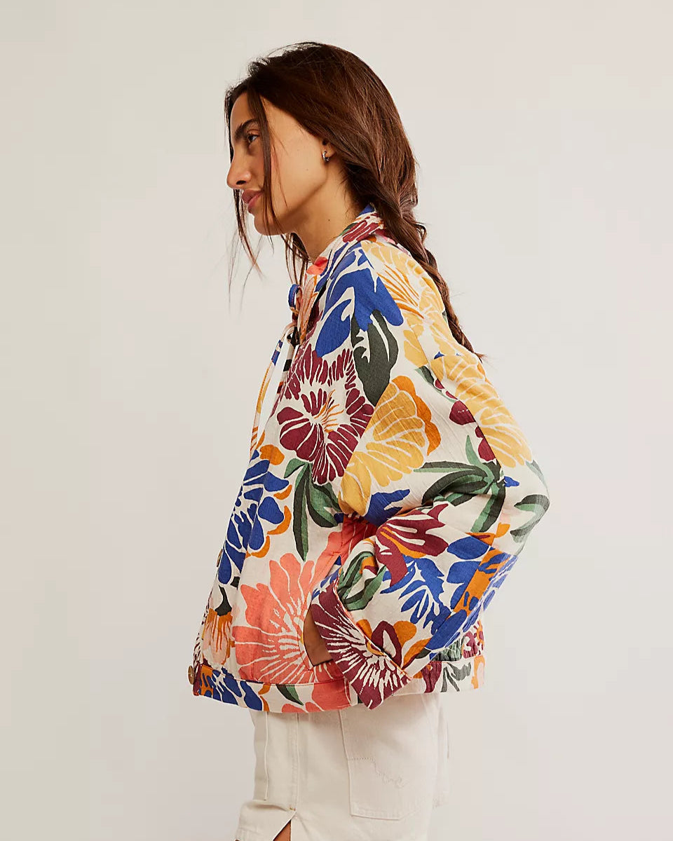 Woman wearing a colorful floral jacket on a plain background