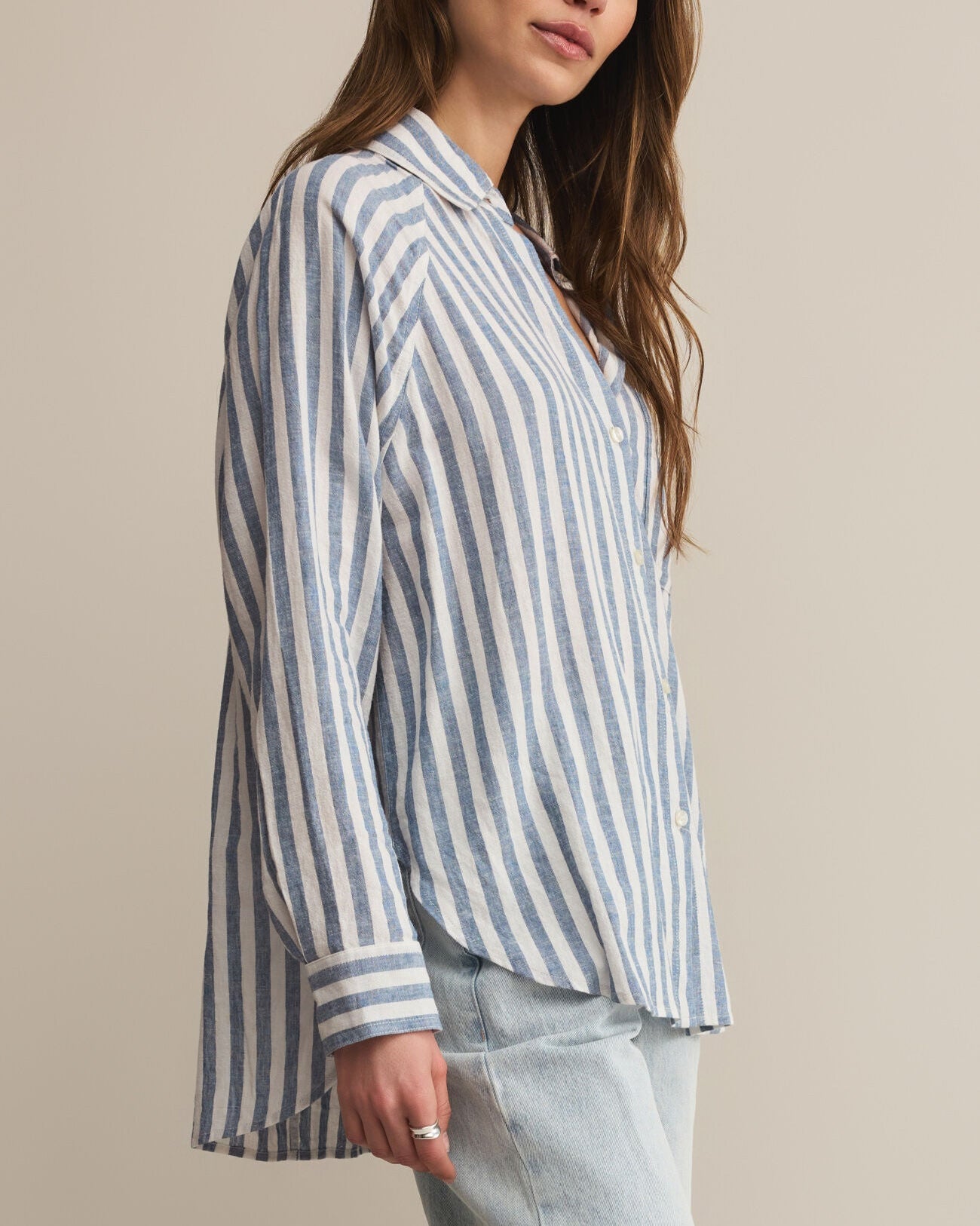 Woman wearing a blue and white striped shirt against a beige background