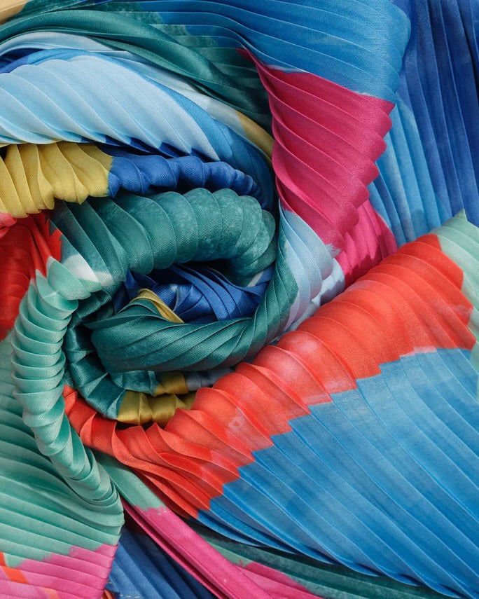 Stack of colorful pleated fabric swatches in various shades.