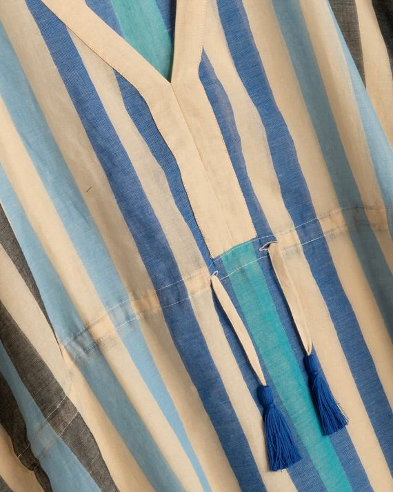 Close-up of a striped fabric with tassels, featuring blue and beige colors.