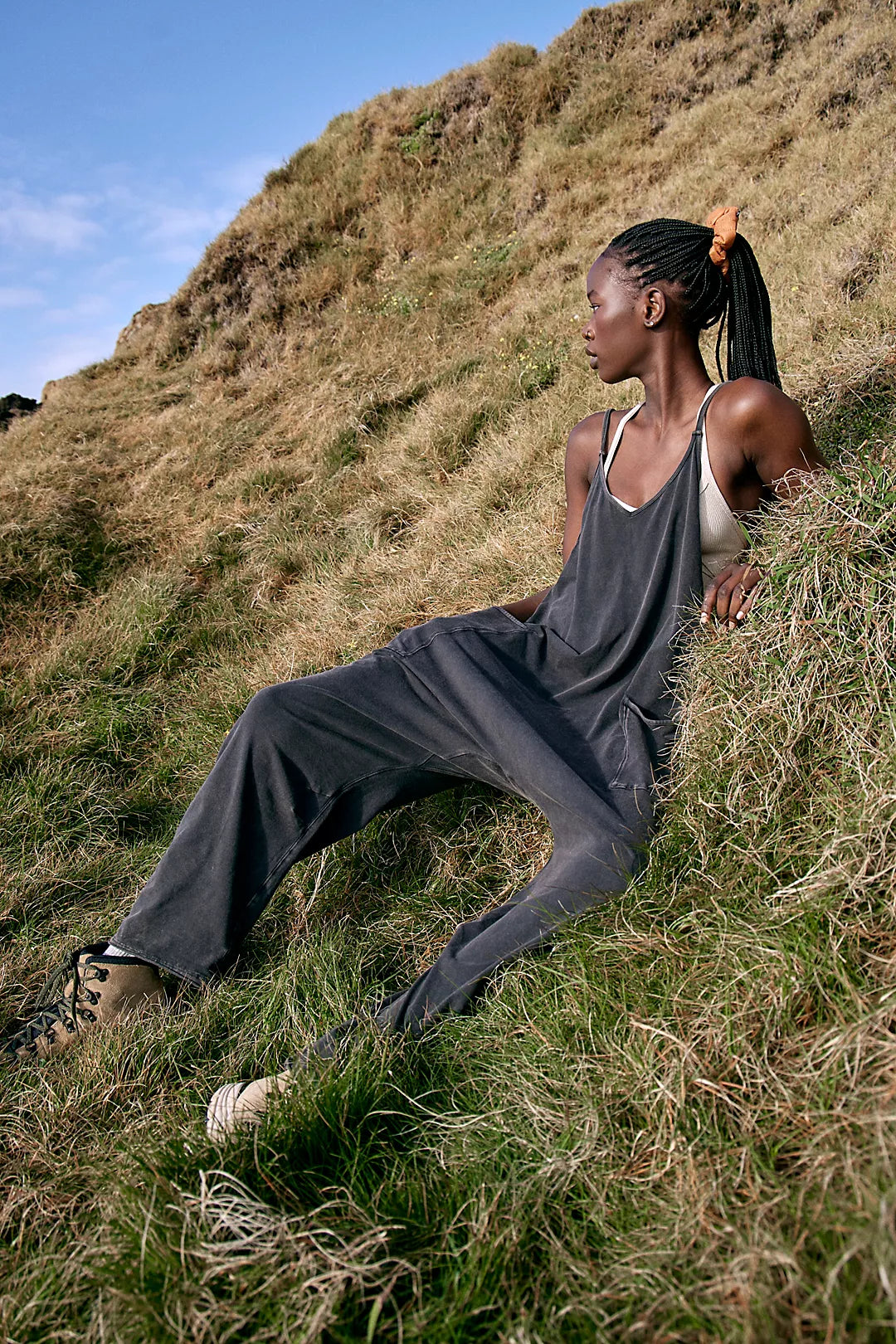Model wearing Free People Hot Shot Onesie in washed black laying on a mountain outside