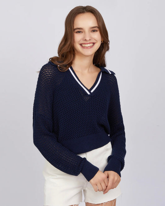 Model wearing 525 America Cara Tipping Navy Polo Pullover sweater wearing white shorts on a white background