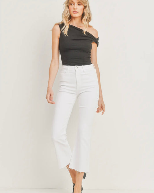 Model wearing Just Black Denim Cropped KIck Flare pants in Optic white wearing a black tank top on a white back ground