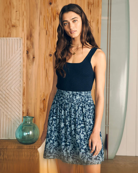 Model wearing Faherty Eliza Mini Skirt wearing Navy blue top standing in front of wooden wall