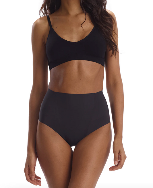 Model wearing Commando Zone Smoothing brief in Black wearing a black bra on a white background